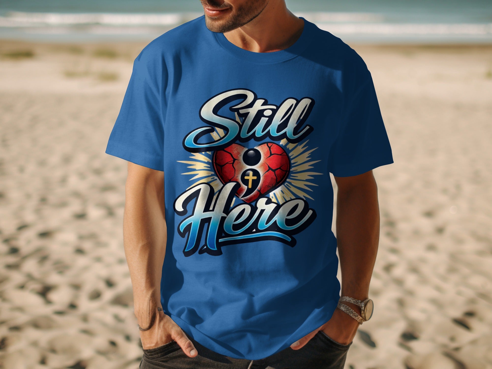 Man wearing a blue t-shirt with "Still Here" text and a heart graphic.