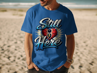 Man wearing a blue t-shirt with "Still Here" text and a heart graphic.