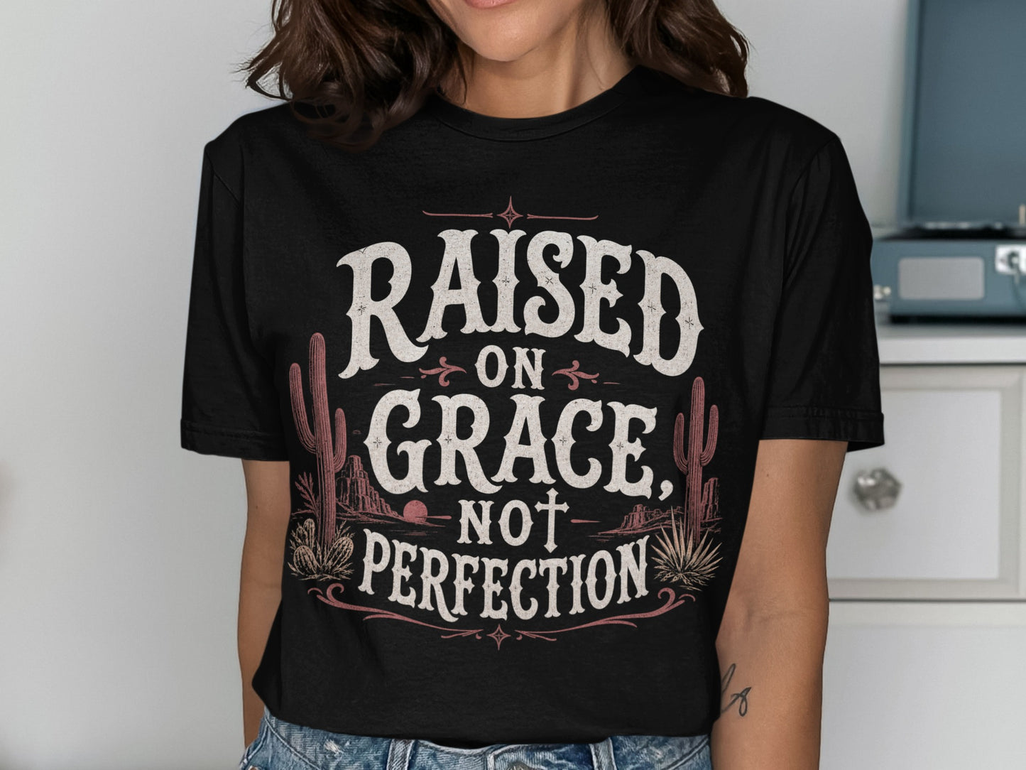 Black t-shirt with "Raised on Grace, Not Perfection" text and desert graphics.