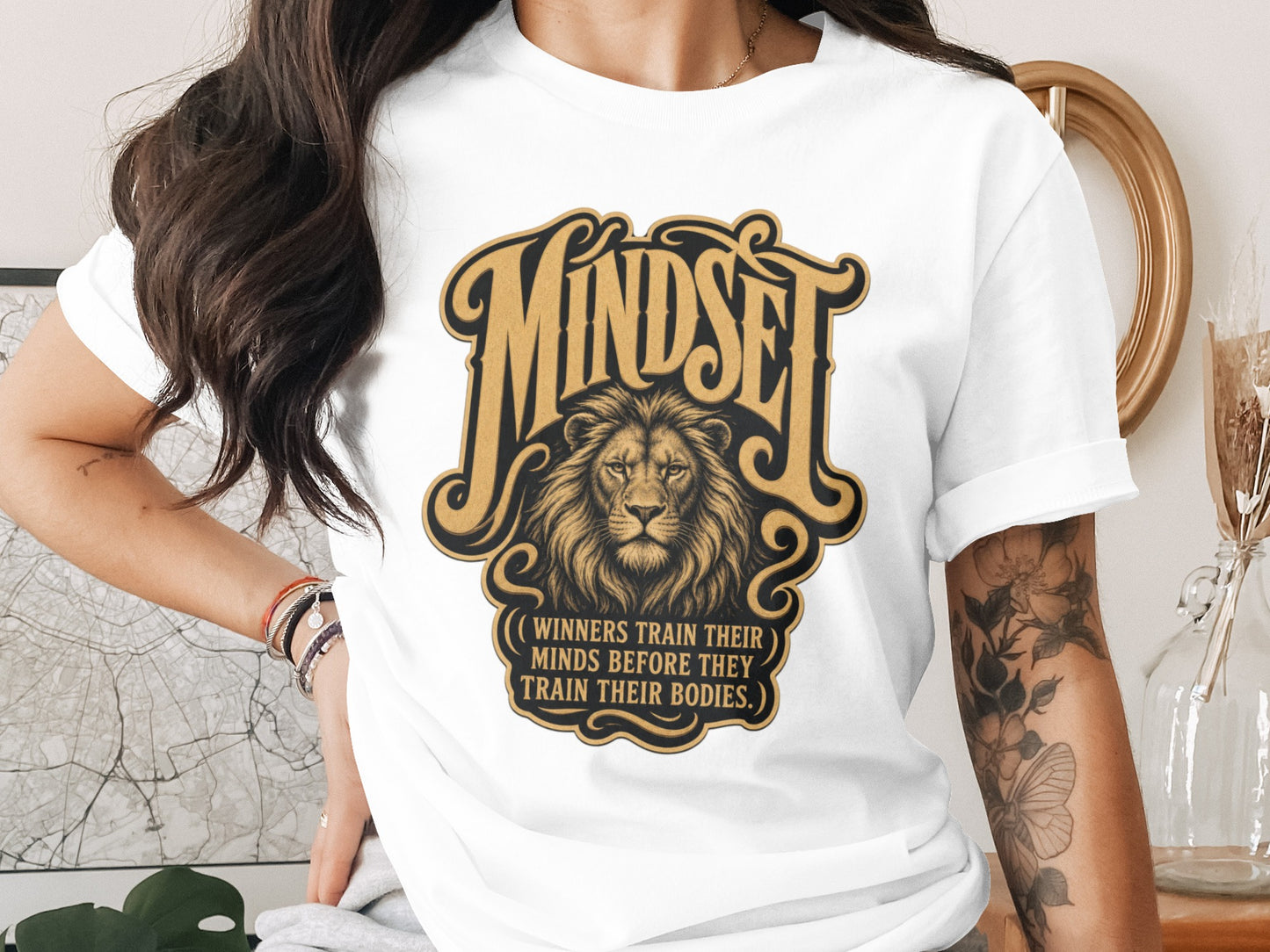 White t-shirt with gold "Mindset" text and a lion, below it reads "Winners train their minds".