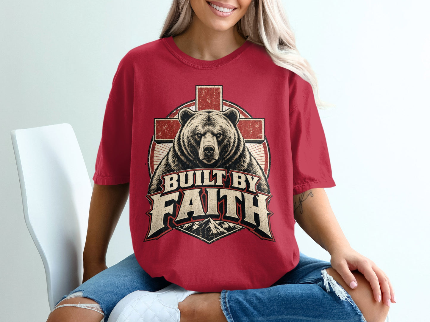 Red t-shirt with a bear and cross graphic reading "Built by Faith."