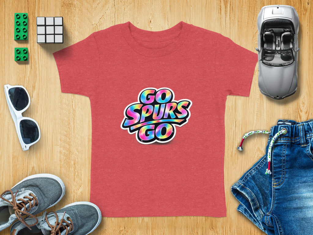 Red t-shirt with rainbow "GO SPURS GO" graphic and surrounding accessories on wood.
