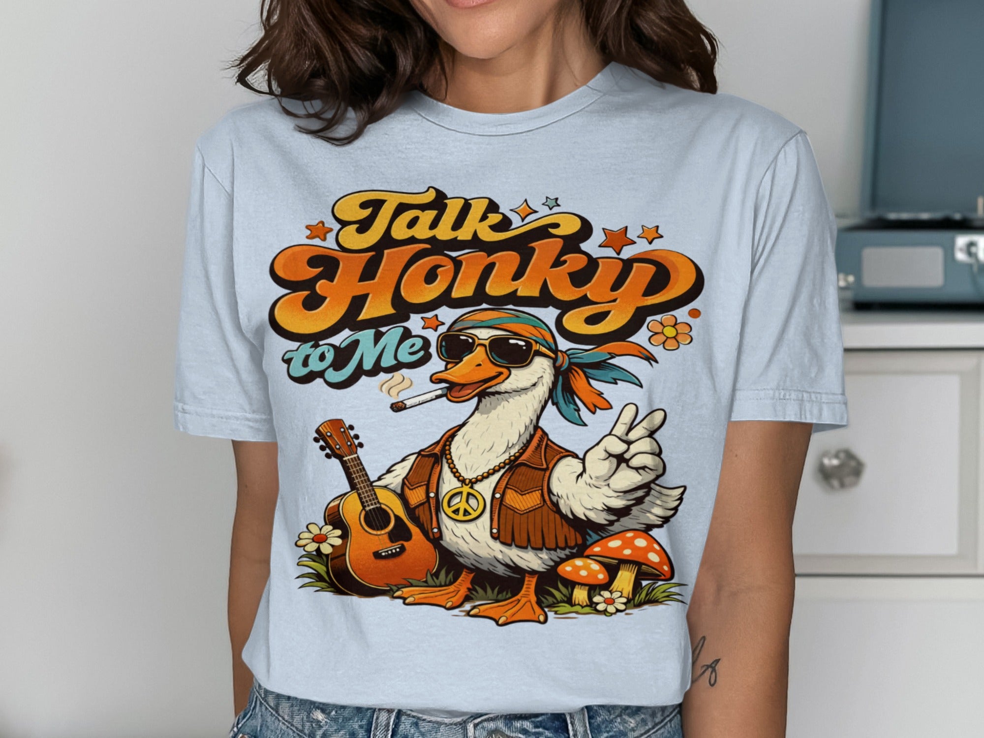 Retro goose with guitar, peace sign, and mushrooms on a light blue t-shirt. "Talk Honky to Me" text.