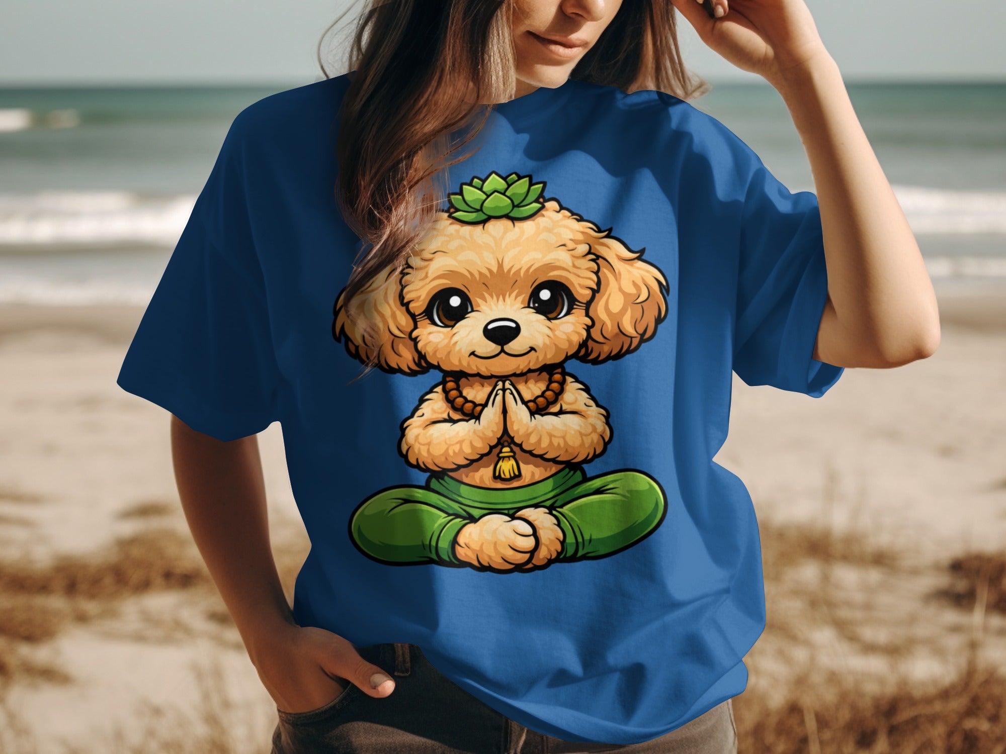 A cartoon dog sits in a meditation pose on a blue t-shirt worn by a person at the beach.