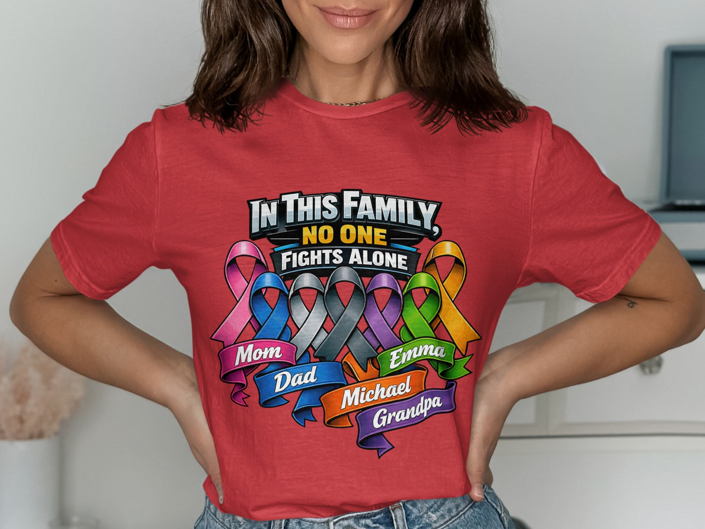 Red t-shirt with "In This Family, No One Fights Alone" and family names on ribbons.