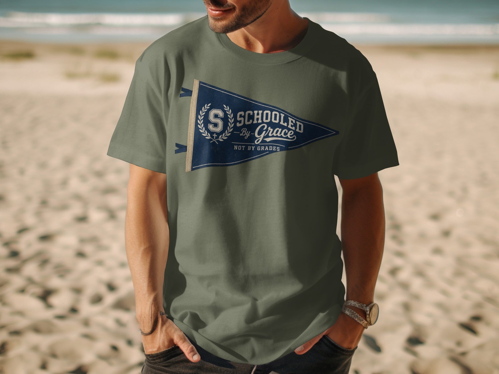 Green t-shirt with a pennant graphic that reads "Schooled by Grace Not by Grades".