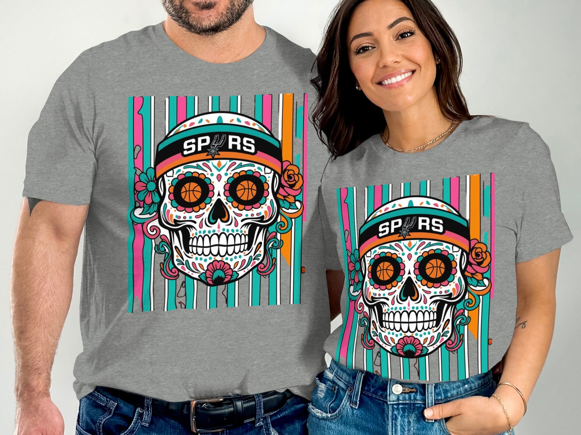 Couple wearing grey t-shirts featuring sugar skull with basketball eyes and "SPURS" text.