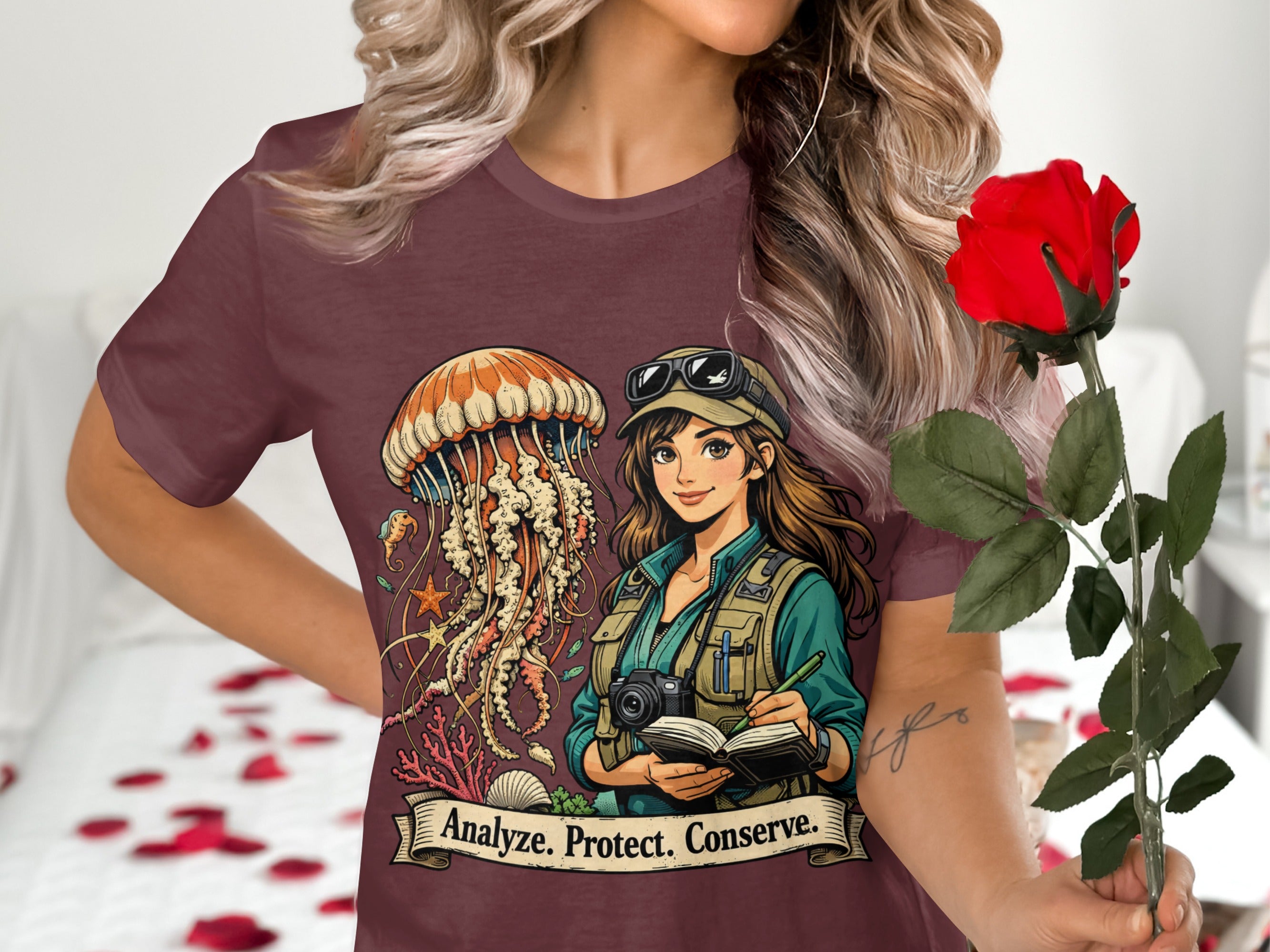 Woman in maroon shirt with graphic of jellyfish, diver, and "Analyze. Protect. Conserve." text.