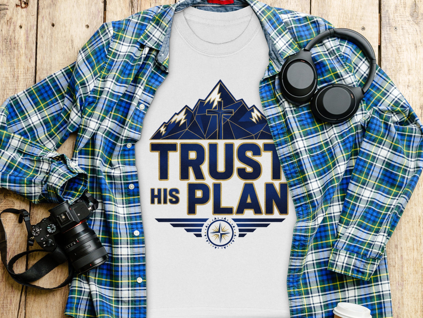 White t-shirt with a graphic that says "TRUST HIS PLAN" and a mountain cross design.