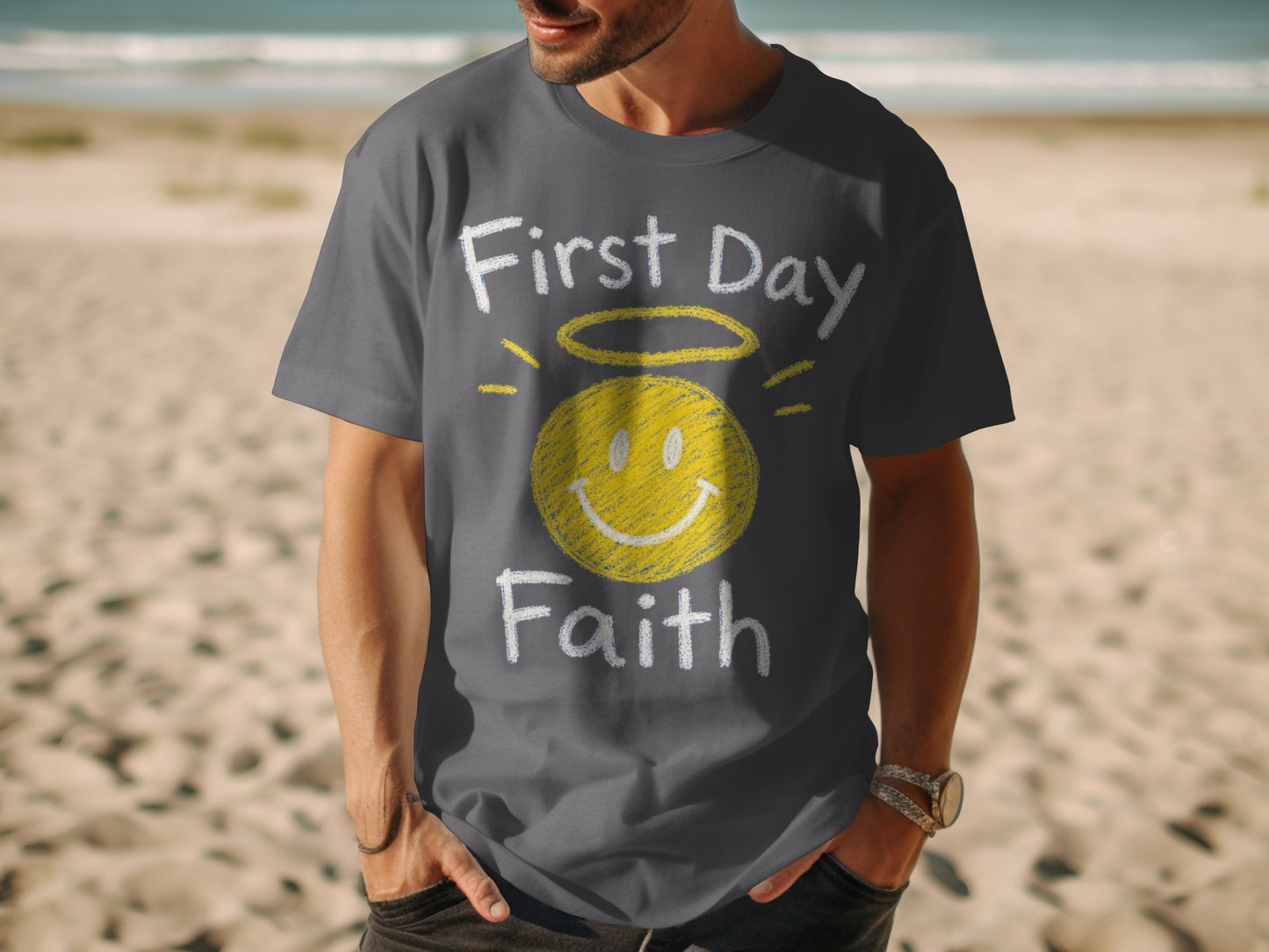 Dark gray t-shirt with yellow smiley face, halo, and text "First Day Faith".