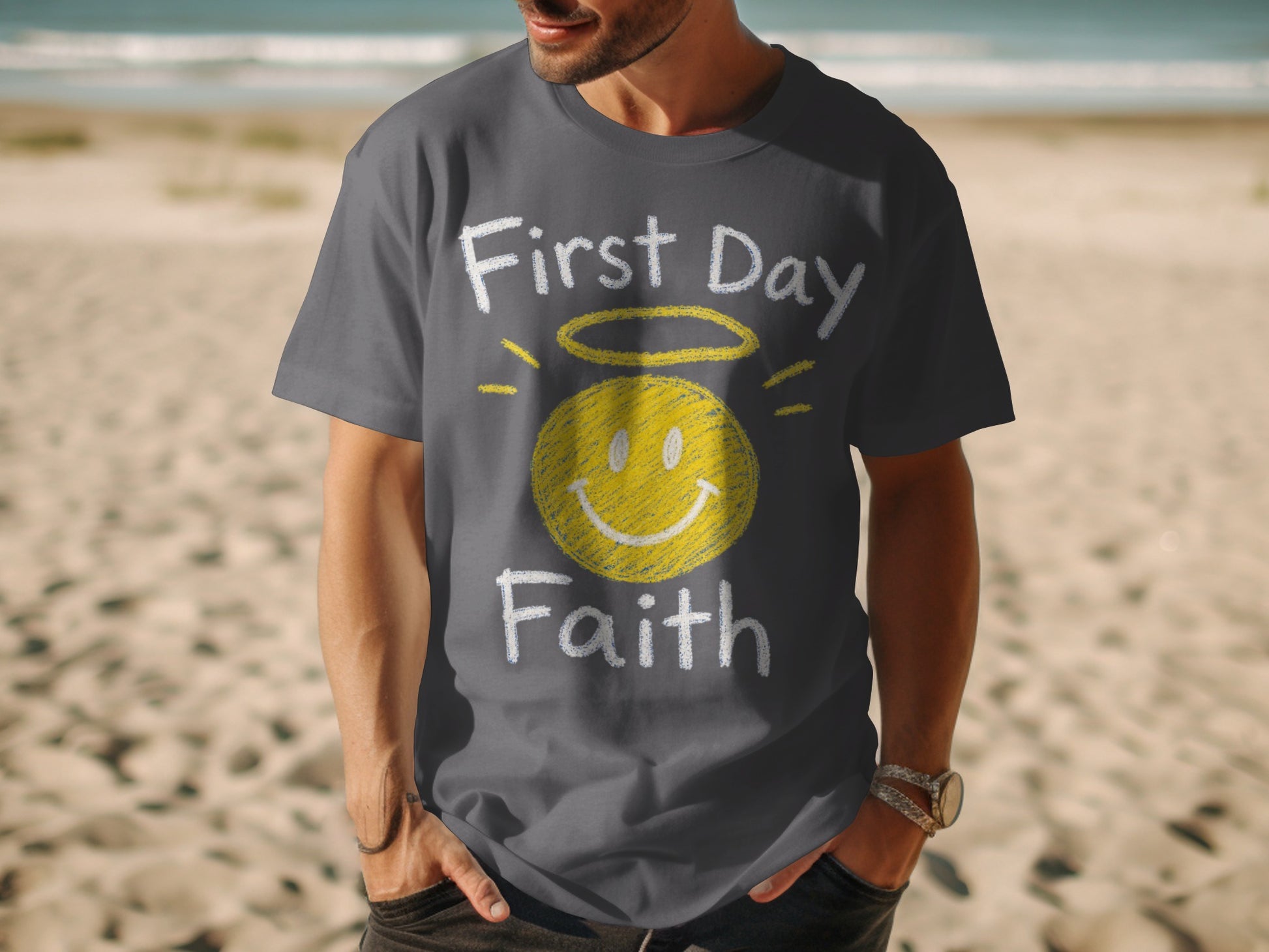 Dark gray t-shirt with yellow smiley face, halo, and text "First Day Faith".