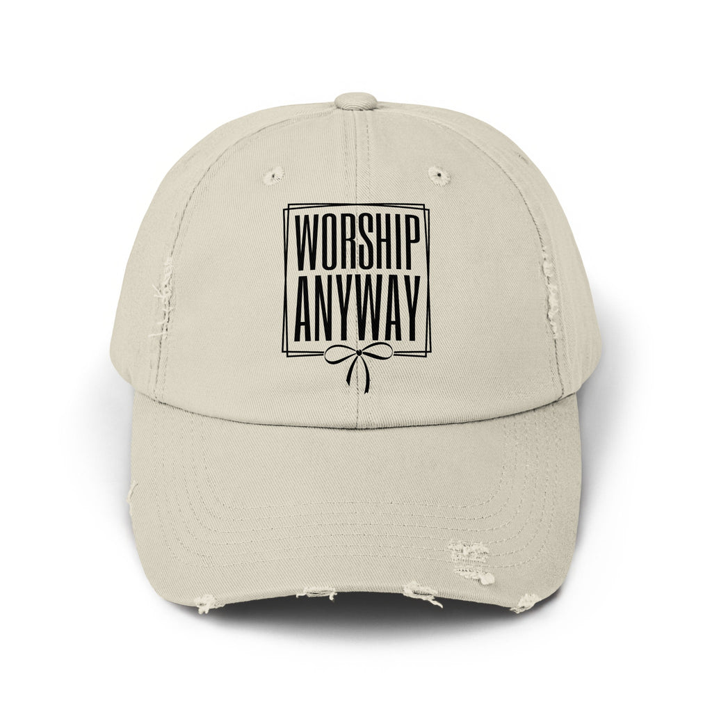 Distressed beige baseball cap with black text "WORSHIP ANYWAY" and a bow design.