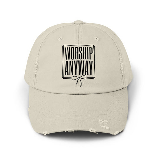Distressed beige baseball cap with black text "WORSHIP ANYWAY" and a bow design.