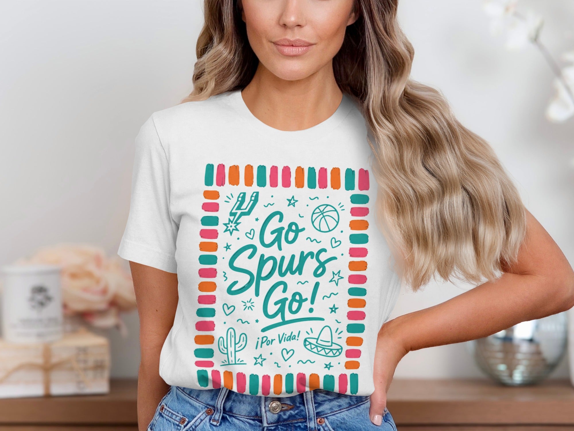 White graphic tee with "Go Spurs Go! ¡Por Vida!" and playful illustrations.