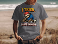 Grey t-shirt with illustration of a sloth wearing a baseball cap, holding a pencil, with text "I TRIED. THAT'S ENOUGH."