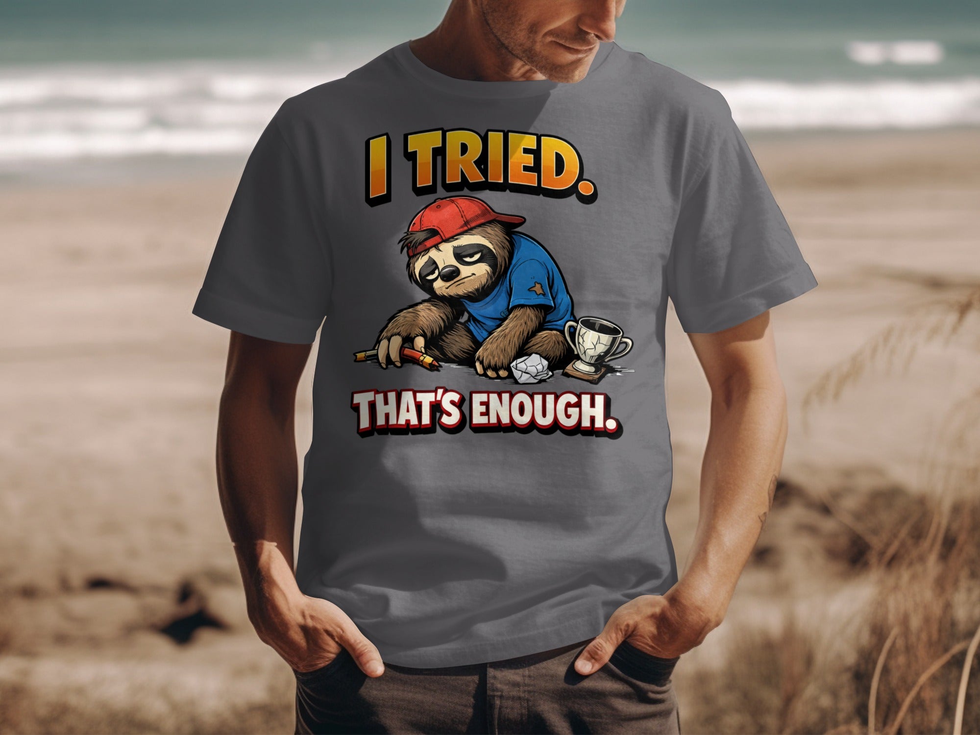 Grey t-shirt with illustration of a sloth wearing a baseball cap, holding a pencil, with text "I TRIED. THAT'S ENOUGH."