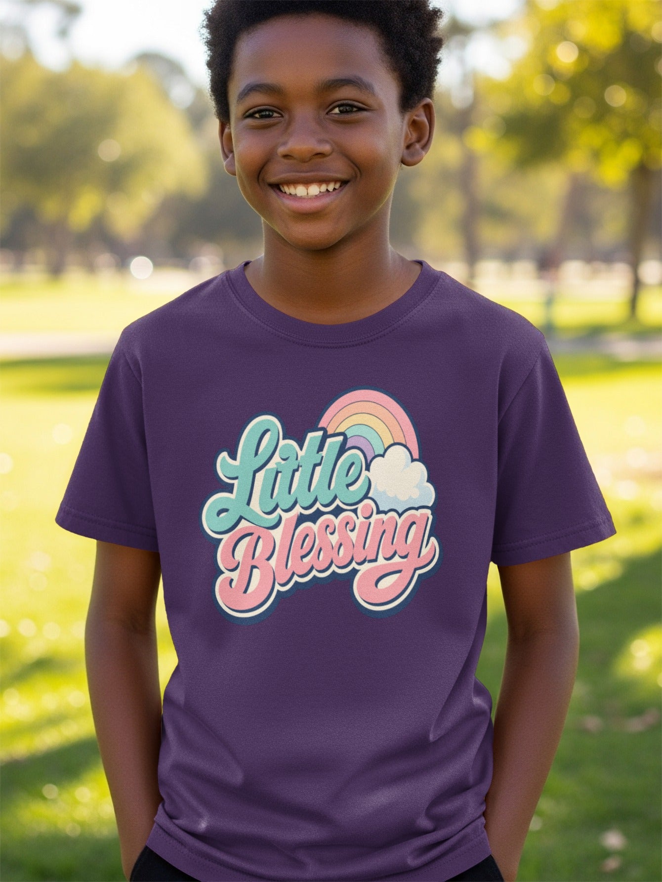 Boy wearing purple t-shirt with "Little Blessing" text and rainbow graphic.