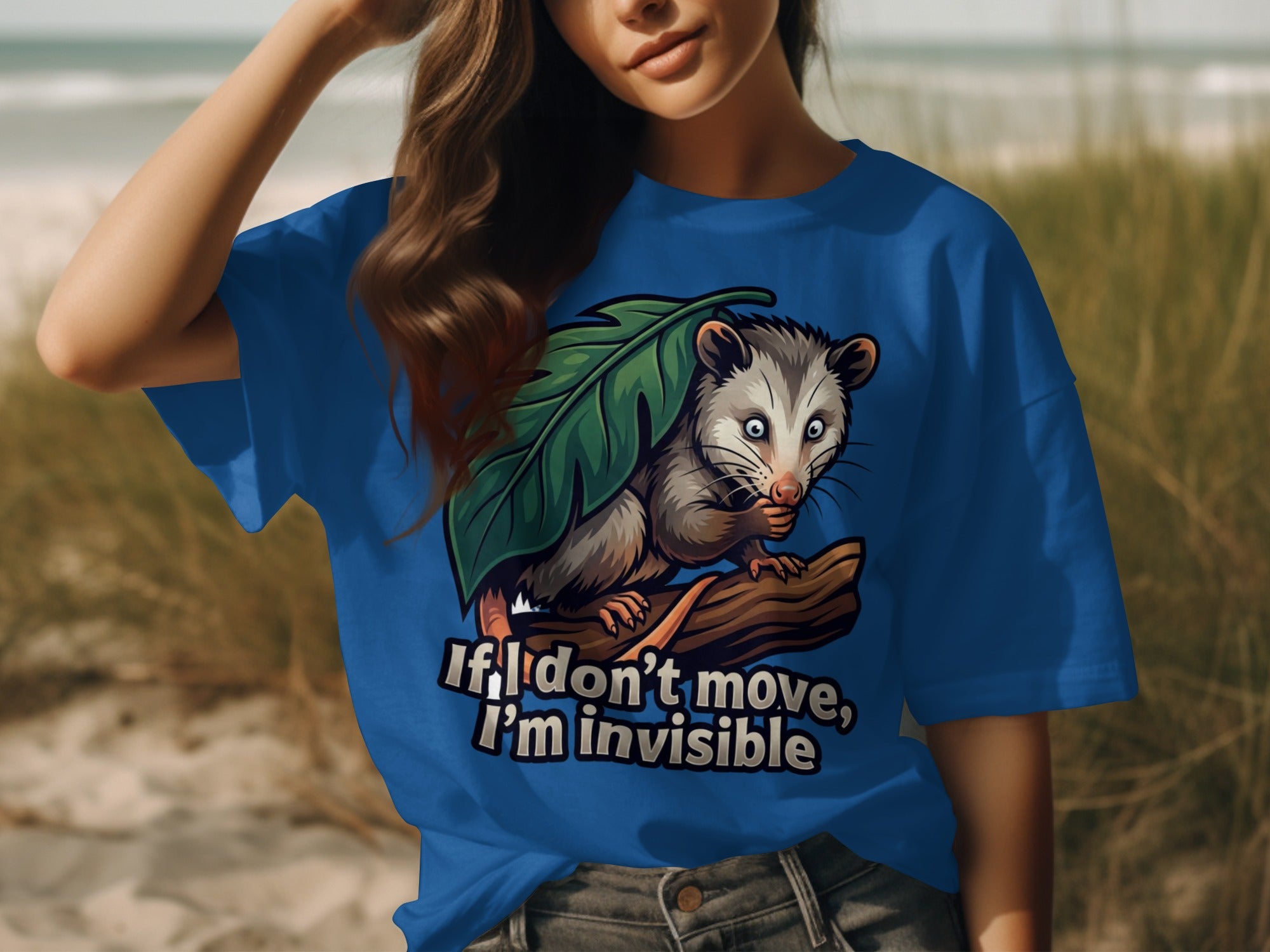 Blue t-shirt with opossum graphic and text "If I don't move, I'm invisible".