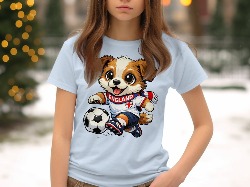 Cartoon dog wearing an England soccer jersey kicks a ball on a light blue t-shirt.