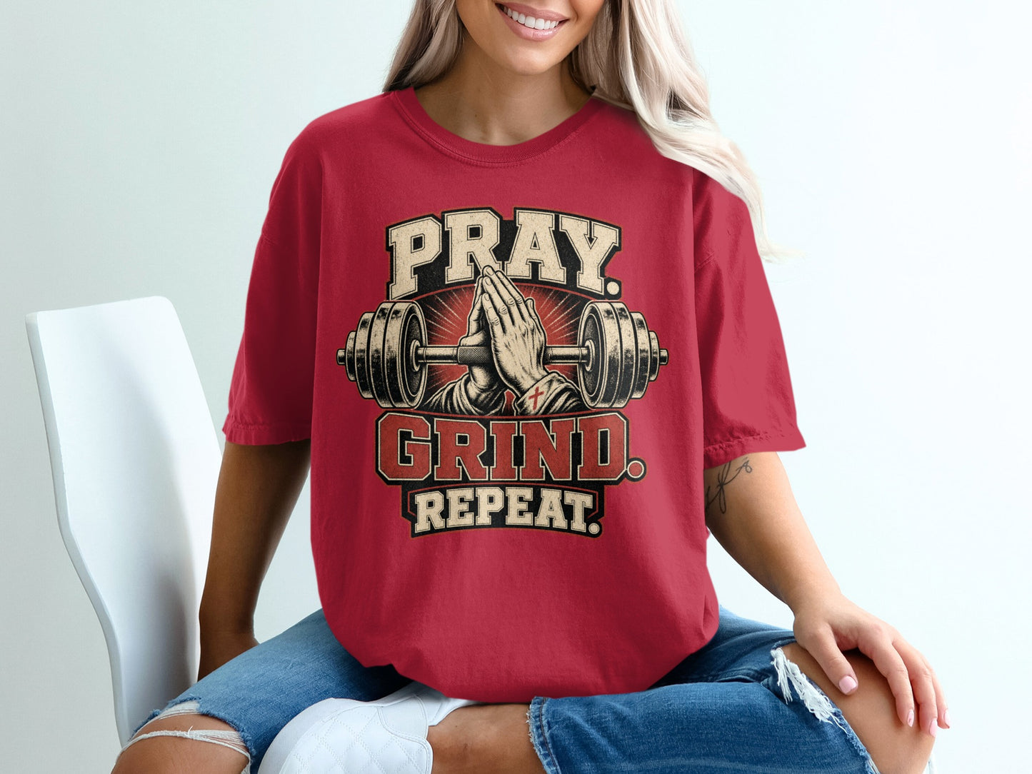 Red t-shirt with Pray Grind Repeat design and barbell hands.