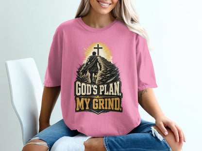 Pink t-shirt with graphic of man climbing path toward cross and text "God's Plan. My Grind."