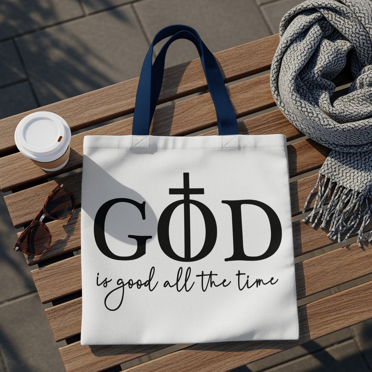 White tote bag with "GOD is good all the time" text and a cross symbol.