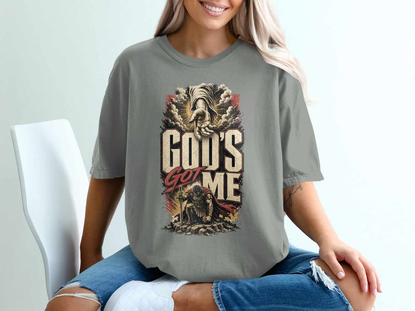 T-shirt with "God's Got Me" text, a reaching hand, and kneeling warrior graphic.