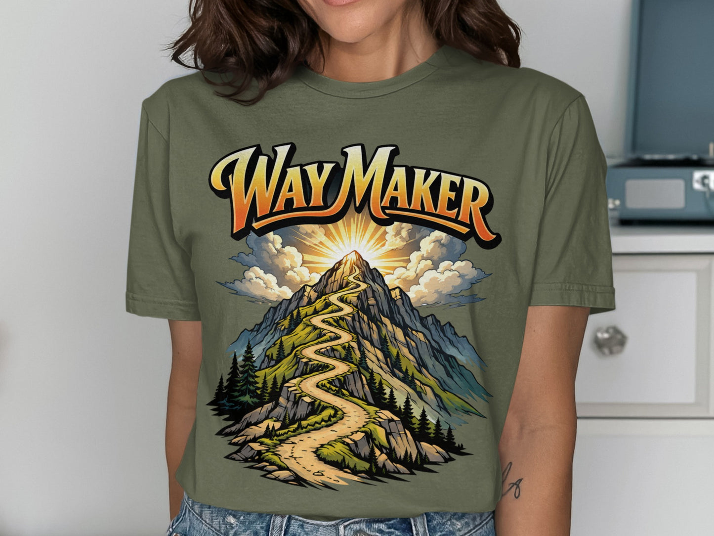 Olive green t-shirt with "Way Maker" text over a winding mountain path.