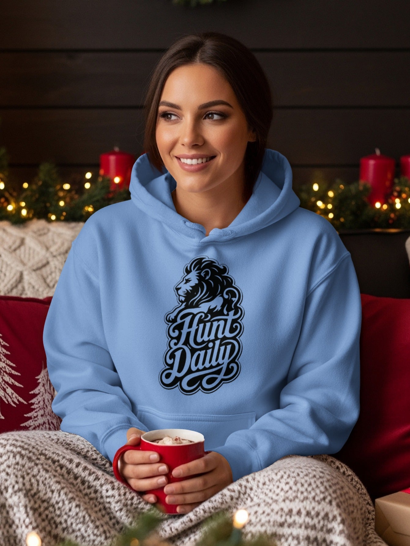 Light blue hoodie with a lion and "Hunt Daily" graphic, held by a woman holding a red mug.