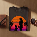 T-shirt with silhouette of woman and child holding hands at sunset with palm trees.