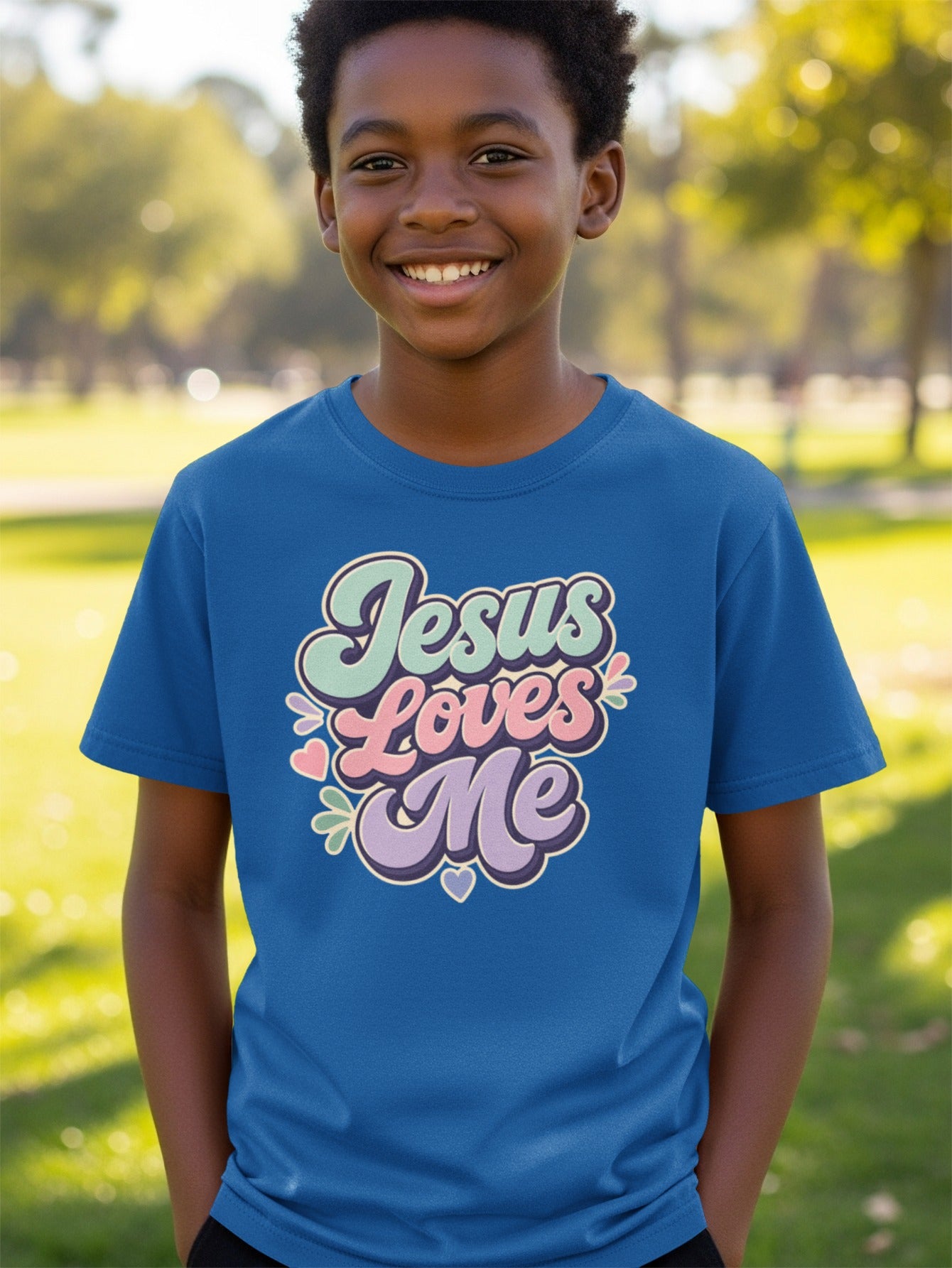 Blue t-shirt with "Jesus Loves Me" in retro pastel lettering and floral accents.