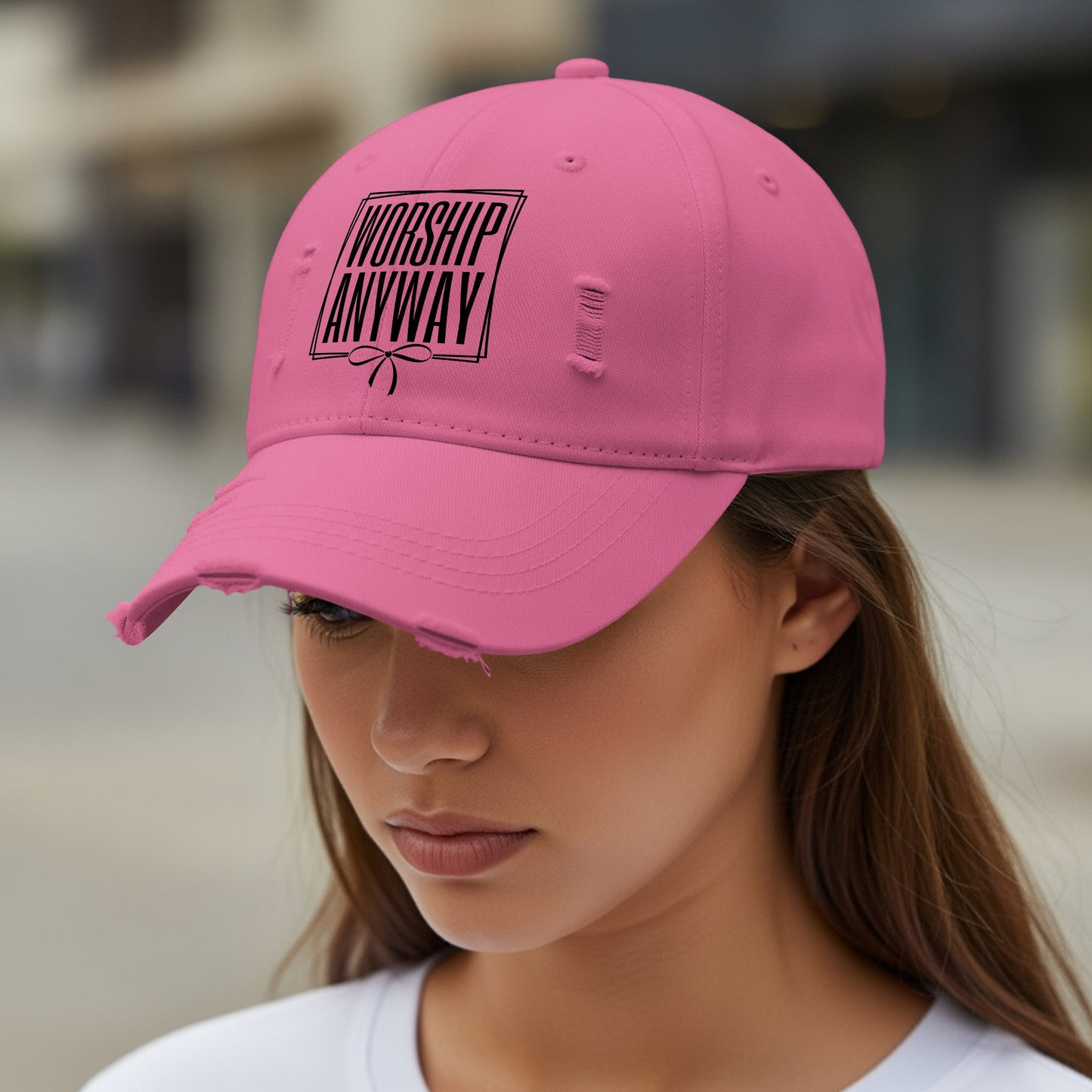 Distressed pink baseball cap with black text "WORSHIP ANYWAY" and a bow.