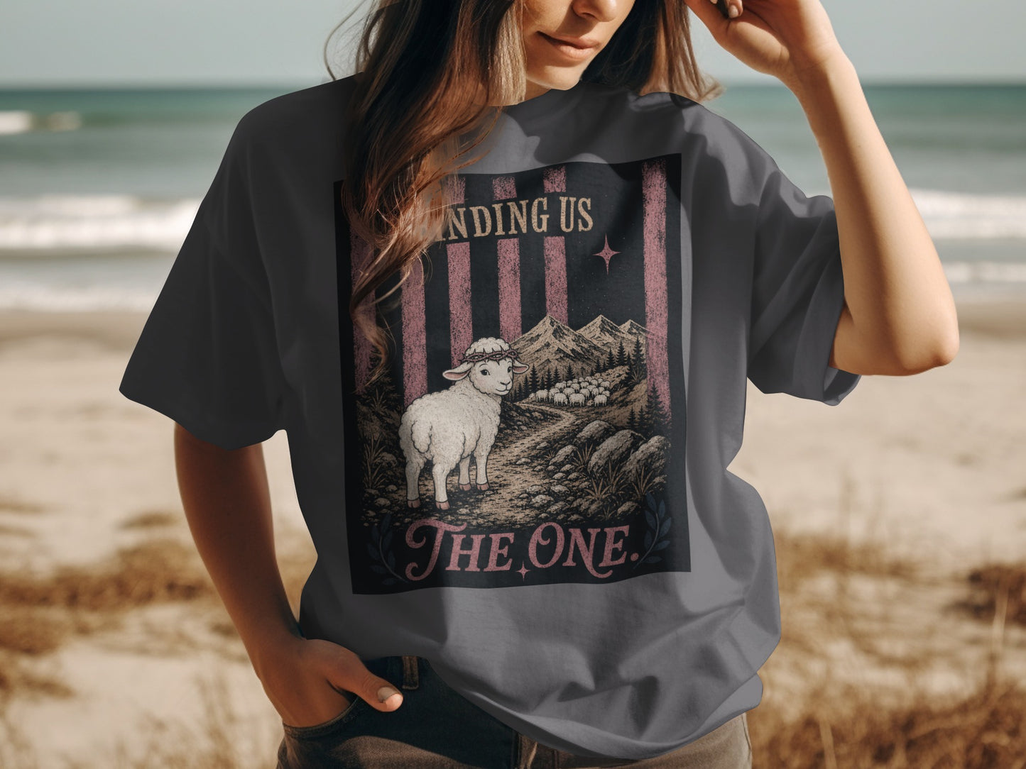 T-shirt graphic with text "FINDING US THE ONE," a lamb, and sheep in a mountain landscape.