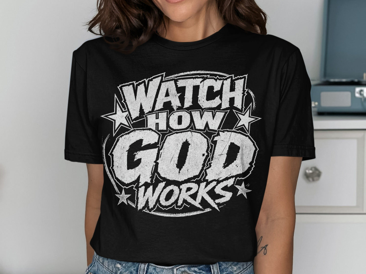 Black t-shirt with white distressed text reading "WATCH HOW GOD WORKS" and stars.