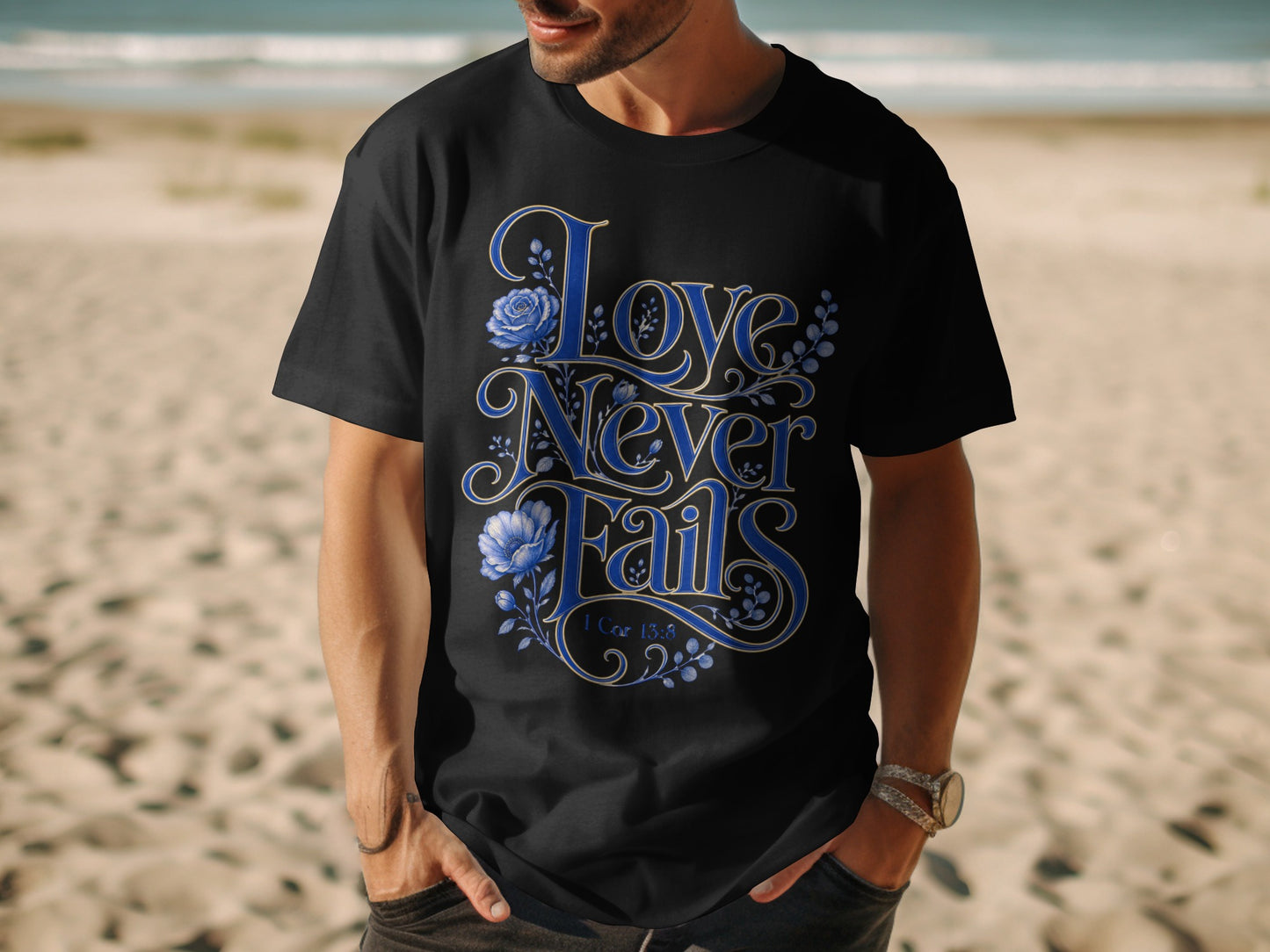 Black t-shirt with blue floral "Love Never Fails" text and 1 Cor 13:8.
