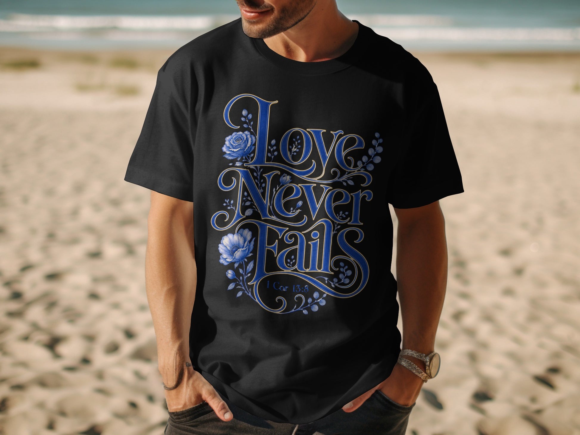 Black t-shirt with blue floral "Love Never Fails" text and 1 Cor 13:8.