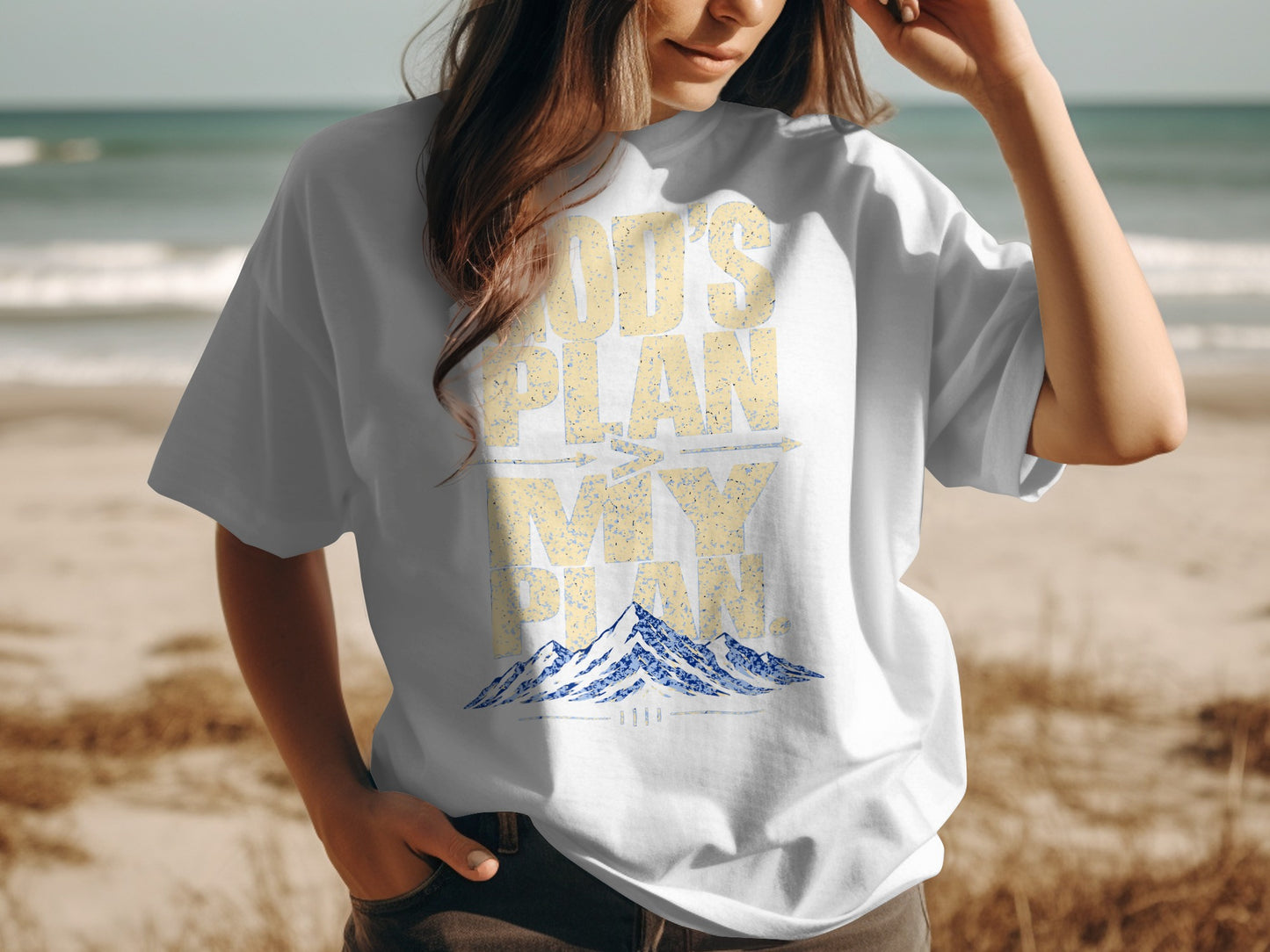 White t-shirt with "God's Plan is Bigger Than My Plan" and mountains graphic.