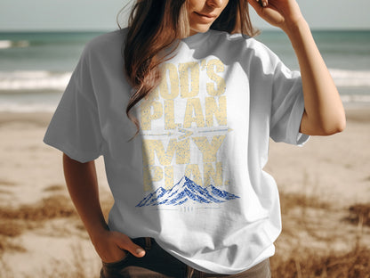 White t-shirt with "God's Plan is Bigger Than My Plan" and mountains graphic.