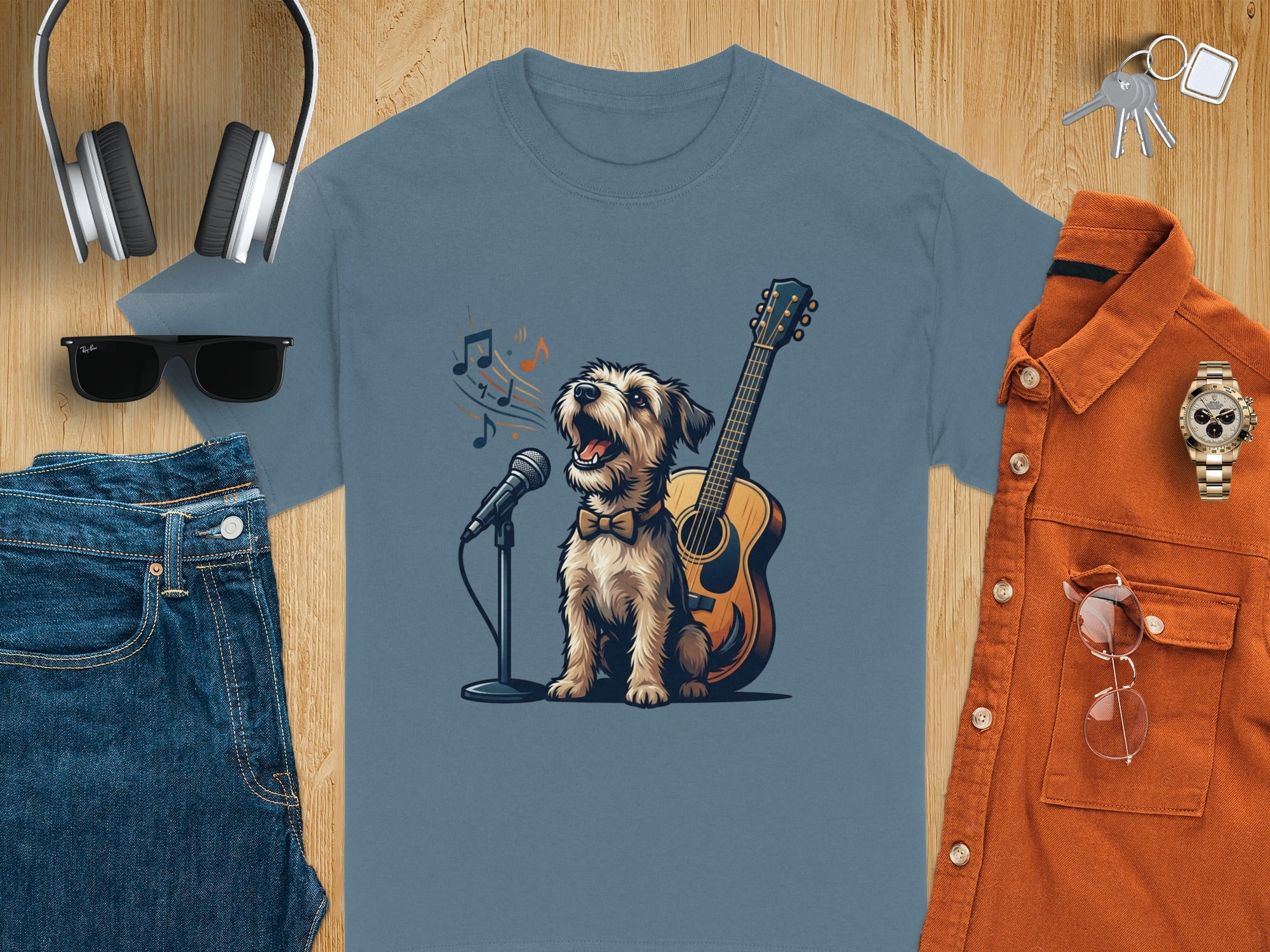 Dog wearing a bowtie sings into microphone next to guitar on blue t-shirt.