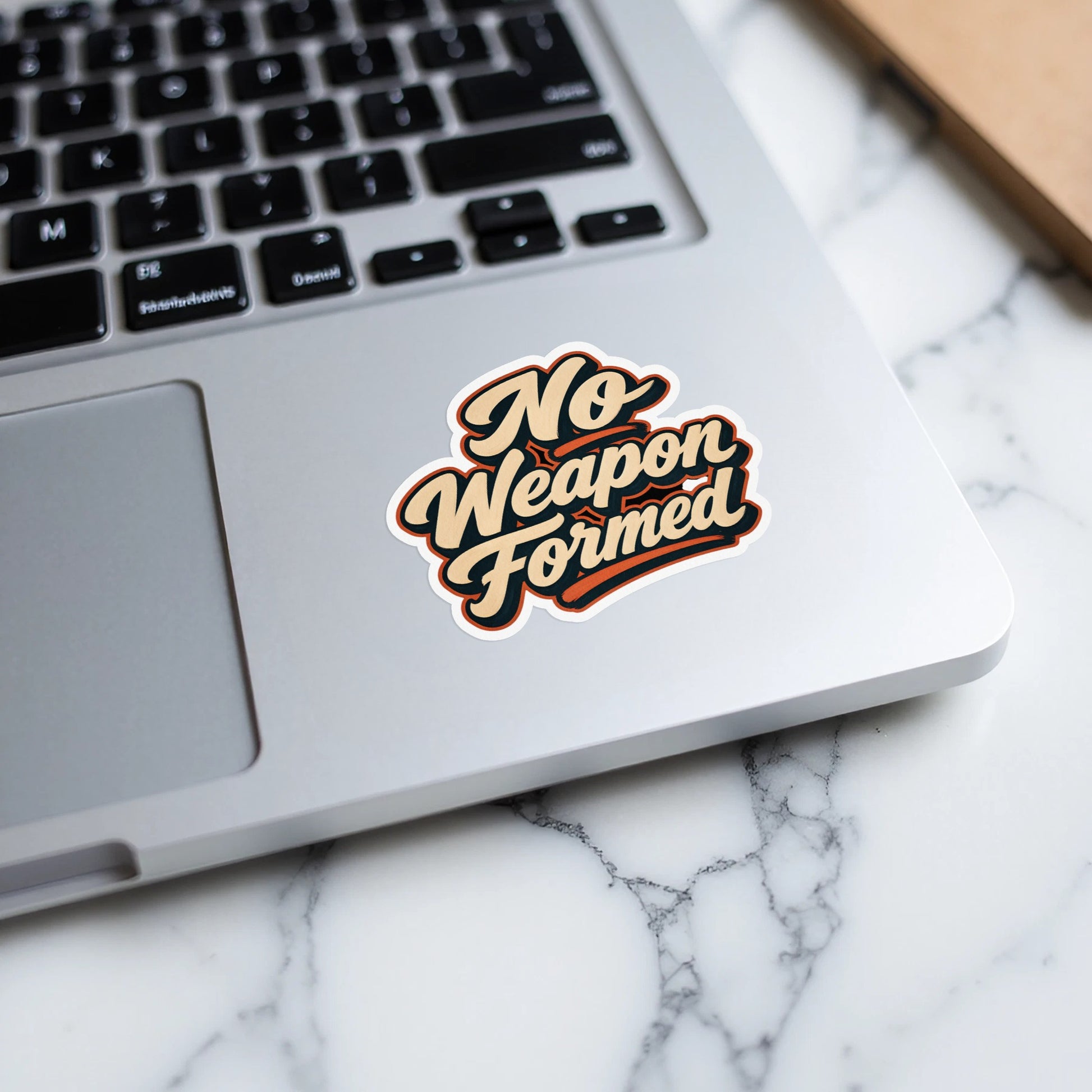 Sticker with "No Weapon Formed" text layered on a laptop keyboard.