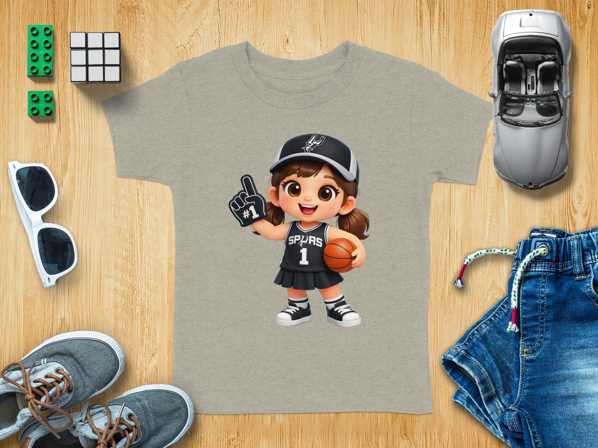 Cartoon girl in basketball uniform with "SPURS" and "1" holds basketball and foam finger.