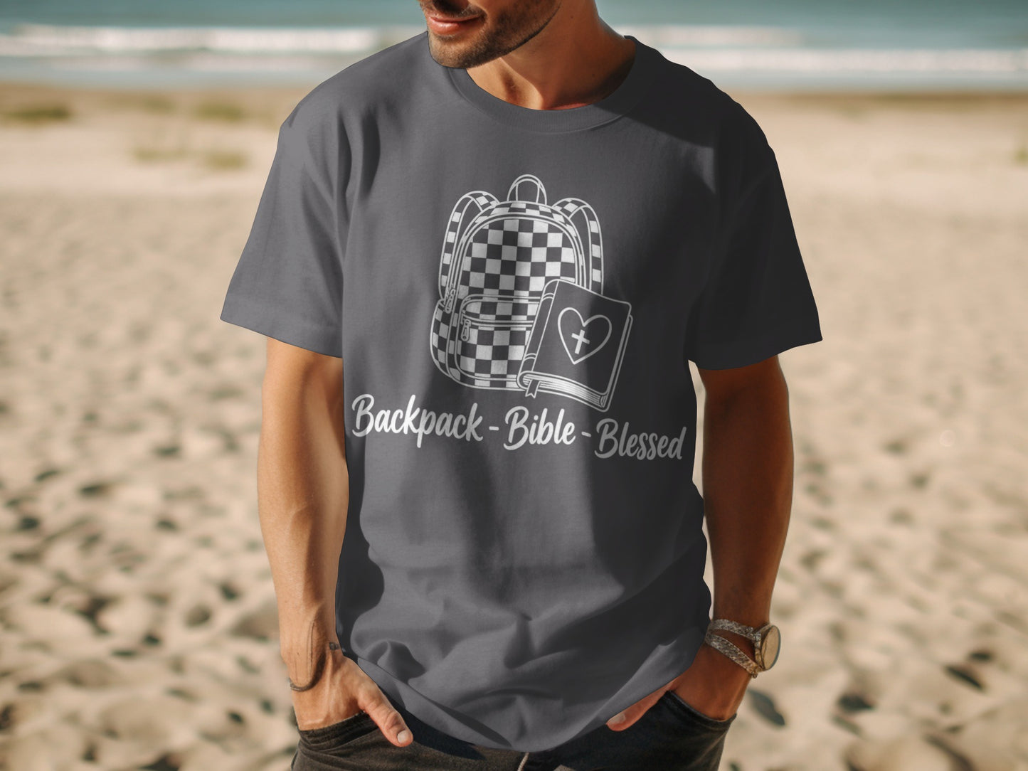 Dark grey t-shirt with white graphic of backpack, Bible, and text "Backpack-Bible-Blessed".