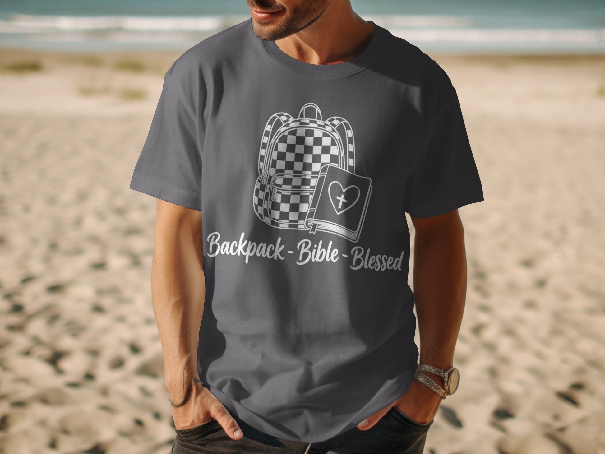 Dark grey t-shirt with white graphic of backpack, Bible, and text "Backpack-Bible-Blessed".