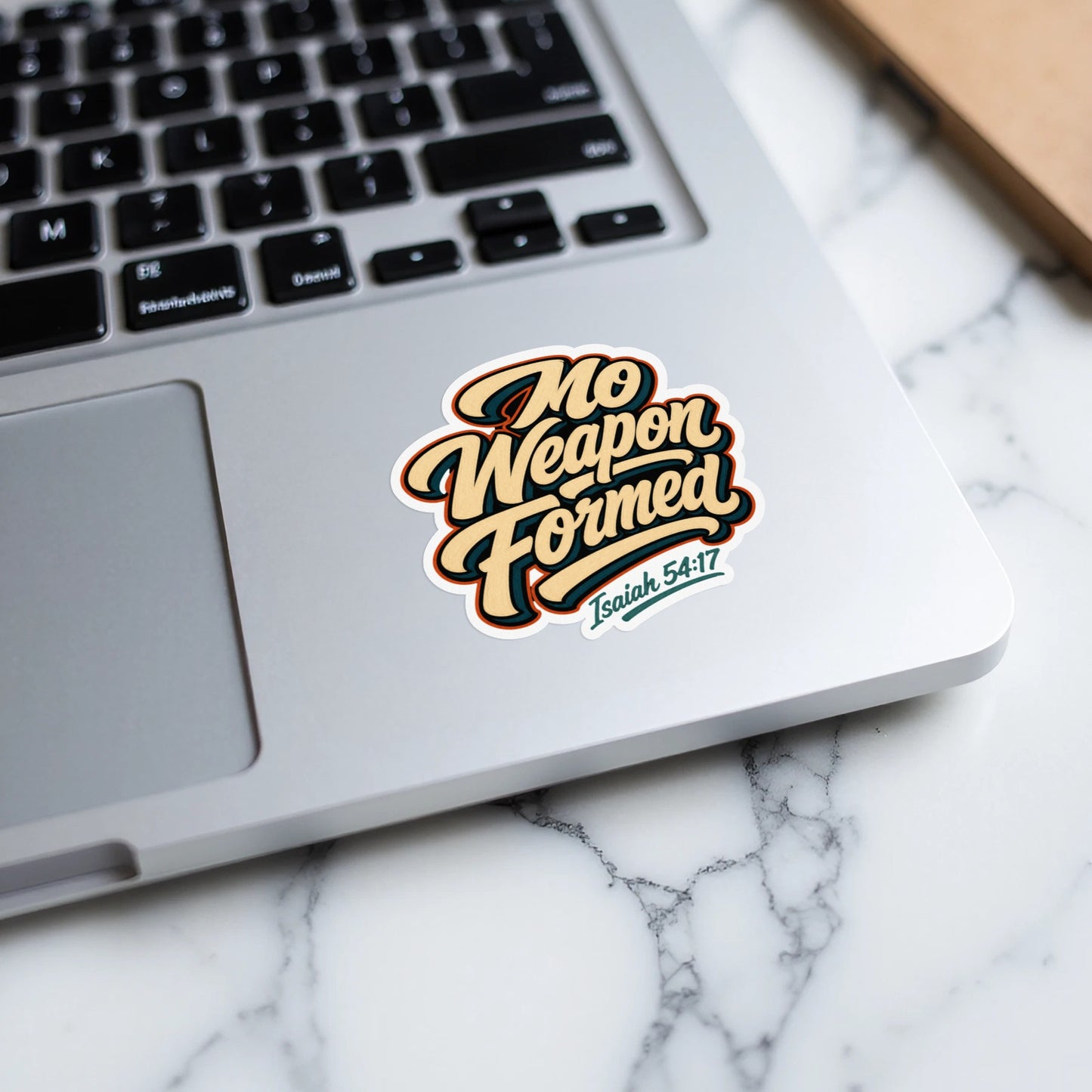 Sticker with "No Weapon Formed" and "Isaiah 54:17" text on a laptop.