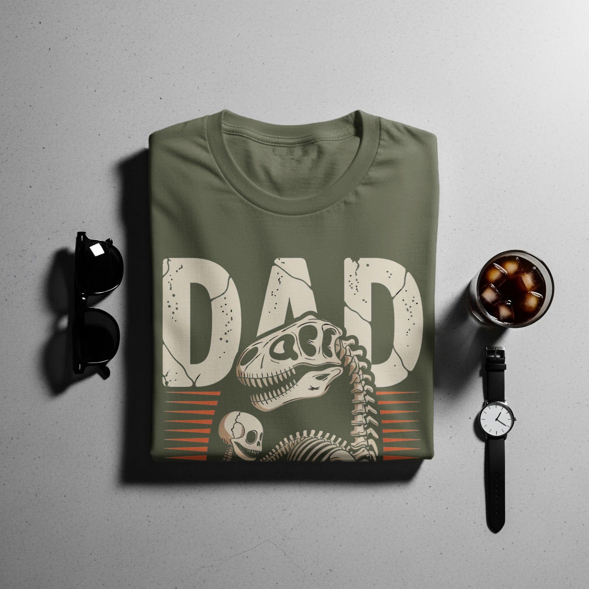 Green t-shirt with "DAD" in cracked letters and dinosaur skeleton graphic.