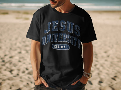 Black t-shirt with "Jesus University Est. 0 AD" text, on a beach.
