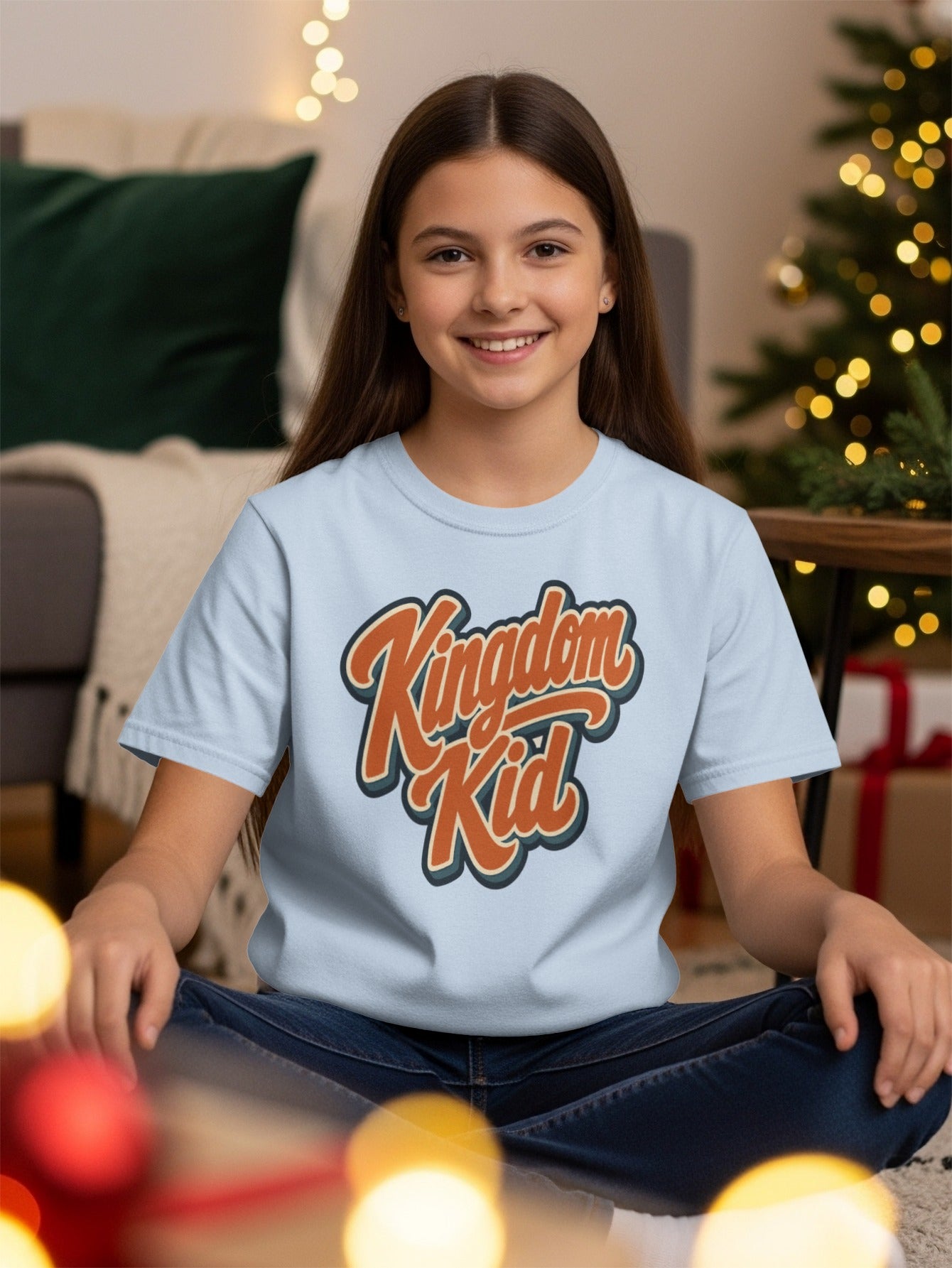 Light blue t-shirt with "Kingdom Kid" graphic, worn by a smiling young girl.