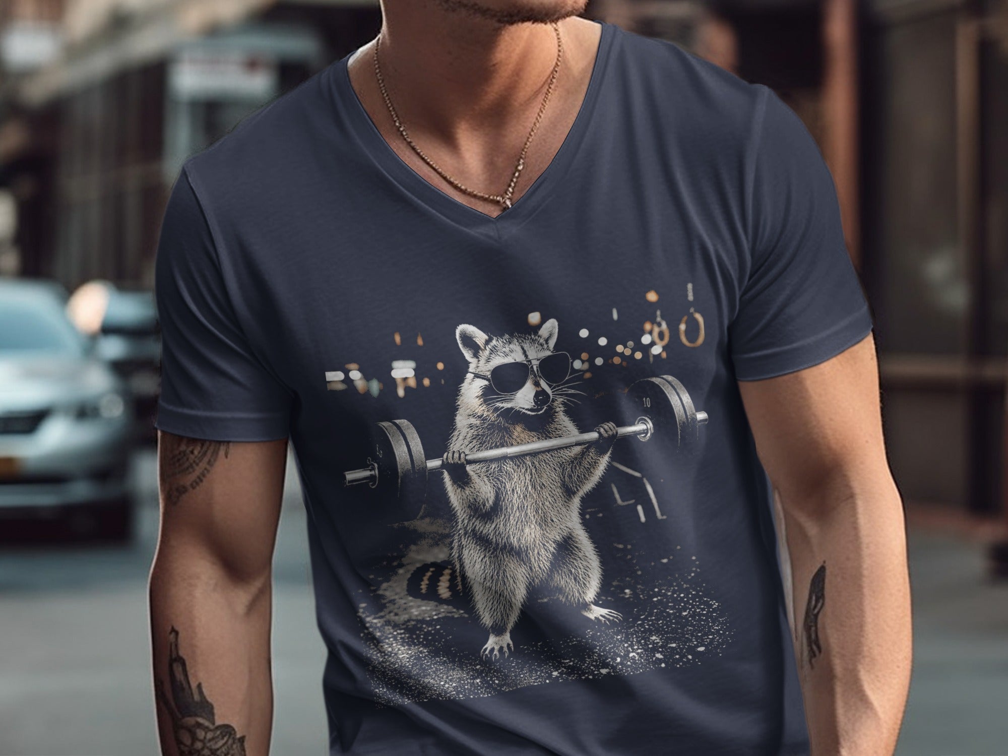 Dark t-shirt with a graphic of a raccoon wearing sunglasses lifting a barbell.