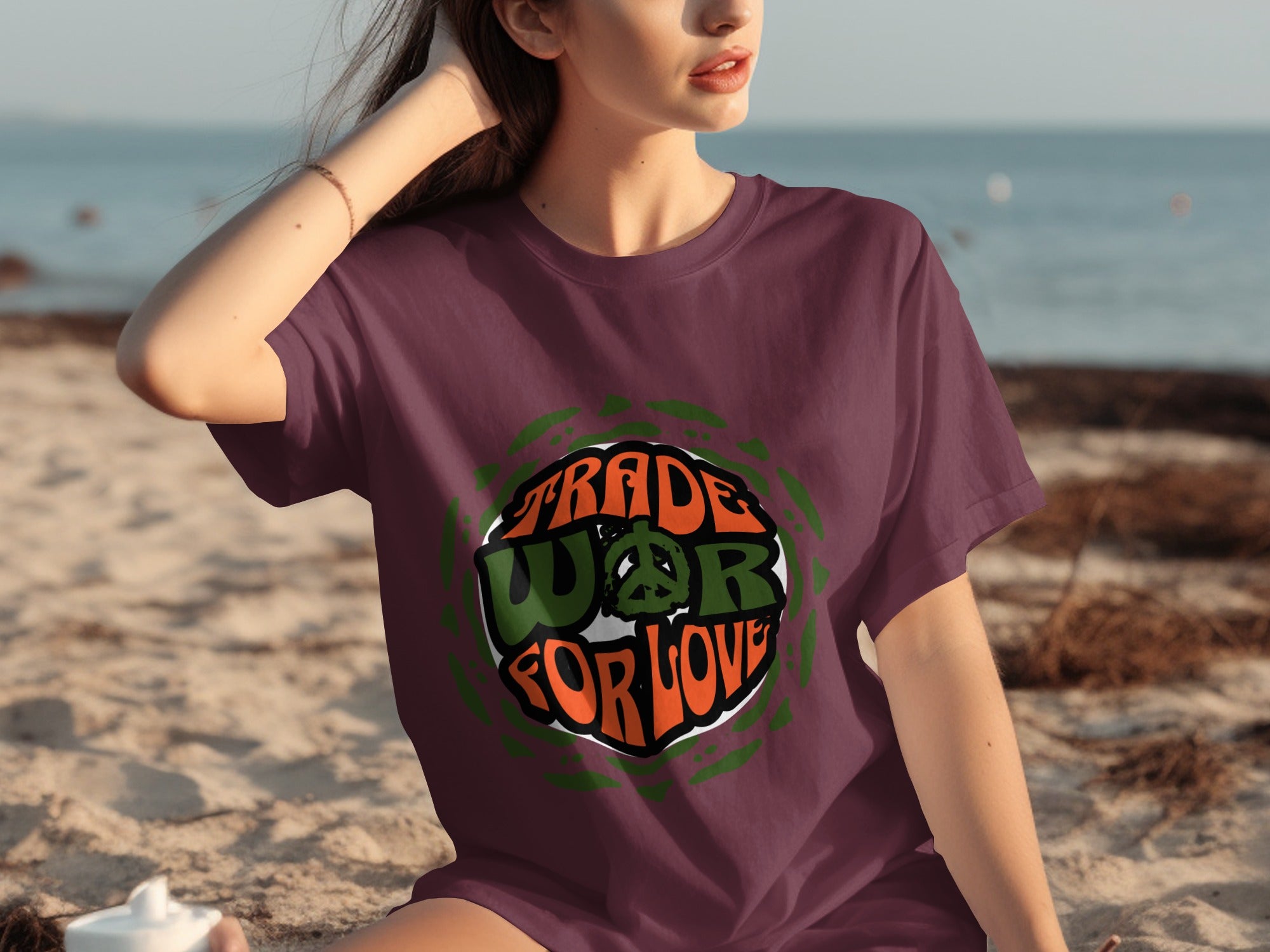 Burgundy t-shirt with "Trade WAR for LOVE" graphic and peace symbol on a beach.