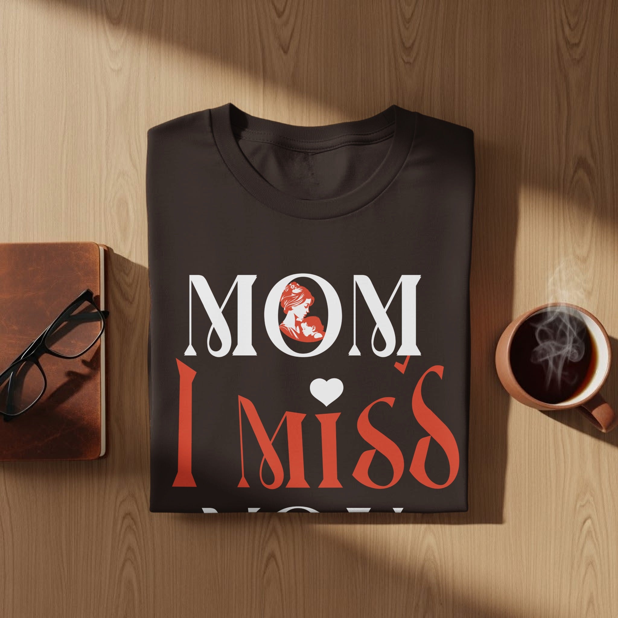 Dark t-shirt with "MOM I Miss" in white and red, featuring an illustration of a mother holding a baby.